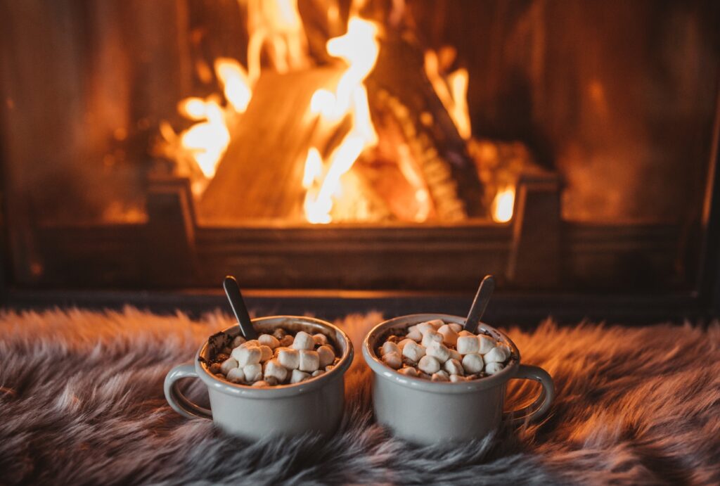 Cozy indoor scene with a fireplace, blankets, and hot chocolate, representing winter comfort. Trust Family Heating & Cooling for reliable furnace repair near me in New Bedford, Fall River, Taunton, and more.