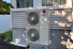 A detailed view of a mini split system installed on an exterior wall, showing its sleek outdoor unit and connection to an outdoor compressor. This energy-efficient mini split system provides personalized heating and cooling for homes and businesses, showcasing how mini splits work without the need for ductwork. Perfect for zoning and maintaining consistent temperatures, this setup highlights Family Heating and Cooling's expertise in professional mini split installation and maintenance services. Call today for expert help with how mini splits work, mini split operation, mini split system functionality, mini split heating and cooling process, how mini split AC systems work, mini split installation near me, how mini split heat pumps work, ductless mini split operation, energy-efficient mini split systems, mini split zoning features, benefits of mini splits, mini split maintenance tips, mini split troubleshooting near me, advantages of mini split systems, professional mini split services near me, mini split indoor and outdoor unit connection, how ductless systems work, and mini split solutions for homes and businesses.