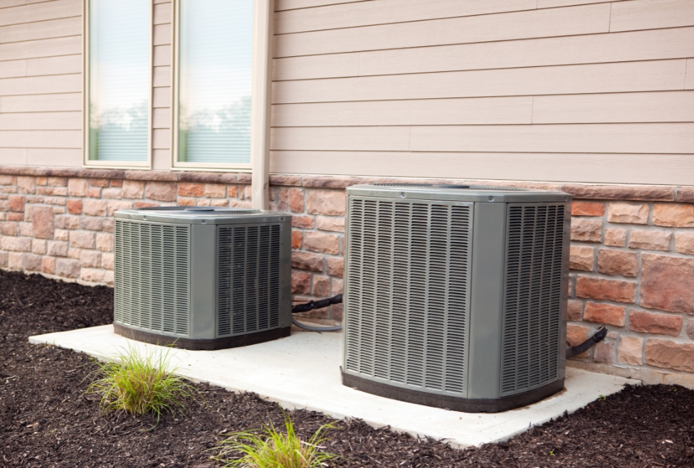 Two outdoor air conditioning units installed next to a building, representing quiet air conditioner options and energy-efficient HVAC systems available through Family Heating and Cooling, including AC installation, AC replacement, and noise-reducing air conditioner models. Call us today for help with quietest air conditioner, best quiet air conditioner, silent air conditioner units, low noise air conditioning system, quiet central air conditioner, quietest AC brands, quiet HVAC system, air conditioner with low decibels, quiet home cooling solutions, quiet AC installation, noise reducing air conditioners, best quiet AC for bedrooms, quietest air conditioner near me, silent AC installation near me, quiet HVAC contractor near me, air conditioner noise control, AC sound blanket installation, air conditioning system noise reduction, quiet air conditioning service, low noise AC repair, whisper-quiet air conditioners, quiet ductless mini split system, best HVAC for noise-sensitive homes.