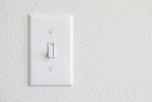 Close-up of a light switch, illustrating what are the 4 types of light switches, including toggle, rocker, dimmer, and smart switches, relevant for residential electrical installation, switch replacement, and professional electrician services by Family Heating, Cooling, Electric and Plumbing. Reach out to us today for help with what are the 4 types of light switches, types of light switches, different light switch types, toggle light switch, rocker light switch, dimmer switch, smart light switch, single-pole switch, three-way switch, four-way switch, light switch installation, light switch replacement, electrical switch wiring, residential electrician services, commercial electrician services, licensed electrician near me, light switch repair near me, switch installation near me, professional electrical services, family heating cooling electric and plumbing electrician services.