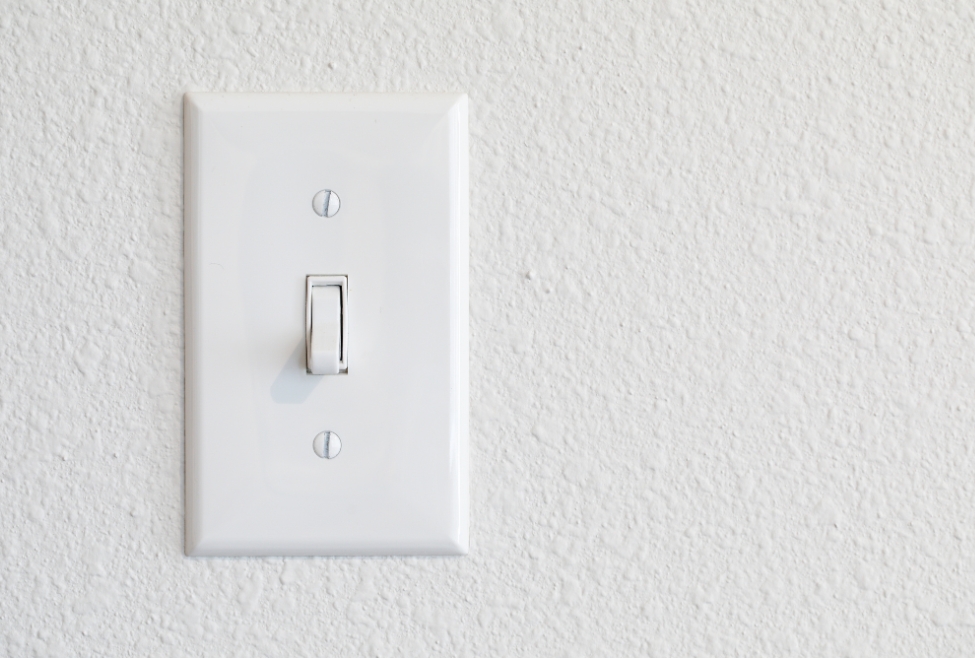 Close-up of a light switch, illustrating what are the 4 types of light switches, including toggle, rocker, dimmer, and smart switches, relevant for residential electrical installation, switch replacement, and professional electrician services by Family Heating, Cooling, Electric and Plumbing. Reach out to us today for help with what are the 4 types of light switches, types of light switches, different light switch types, toggle light switch, rocker light switch, dimmer switch, smart light switch, single-pole switch, three-way switch, four-way switch, light switch installation, light switch replacement, electrical switch wiring, residential electrician services, commercial electrician services, licensed electrician near me, light switch repair near me, switch installation near me, professional electrical services, family heating cooling electric and plumbing electrician services.