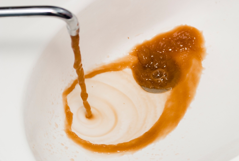 Running faucet showing rusty or discolored hot water with brown and orange tint caused by water heater corrosion, sediment buildup, or aging plumbing pipes, indicating potential need for water heater repair, plumbing inspection, and water quality troubleshooting by Family Heating, Cooling, Electric and Plumbing. Contact us today for help with rusty or discolored hot water, brown hot water from tap, orange water from faucet, yellow water coming from sink, dirty hot water problem, hot water discoloration issues, why is my hot water brown, rusty water from water heater, water heater rust contamination, sediment in hot water tank, corroded water heater symptoms, anode rod failure water heater, water heater repair near me, plumbing inspection near me, water quality issues home plumbing, emergency plumber near me discolored water, hot water heater flushing service, water heater maintenance near me, residential plumbing services near me, water heater replacement near me, hot water smells metallic or rusty, inconsistent water color faucet, galvanized pipe rust water issues, whole house water discoloration troubleshooting, Family Heating Cooling Electric and Plumbing water heater service, licensed plumber water discoloration repair near me, emergency water heater diagnostics, hot water not clear repair service, home plumbing corrosion inspection near me.