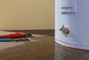 Leaking water heater with water pooling around the base, showing signs of water heater leaking, tank corrosion, and plumbing issues that may require water heater repair or leak detection from Family Heating, Cooling, Electric and Plumbing. Call us now for help with water heater leaking, leaking water heater, hot water heater leaking, water heater leaking from bottom, water heater leaking from top, water heater leaking from pressure relief valve, water heater leaking from drain valve, water heater tank leaking, emergency water heater repair, water heater leak repair, leaking hot water tank repair, plumber for leaking water heater, water heater replacement near me, water heater repair near me, leaking water heater near me, hot water tank leaking near me, residential plumbing repair near me, emergency plumber near me, water heater maintenance near me, tankless water heater leaking, gas water heater leaking, electric water heater leaking, water heater corrosion repair, water heater pressure valve replacement, plumbing leak detection near me, water heater inspection service, home plumbing services near me, Family Heating Cooling Electric and Plumbing water heater service, same day water heater repair near me.