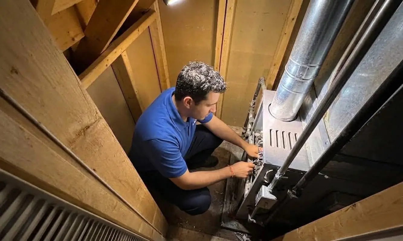 Technician servicing a furnace in a basement.